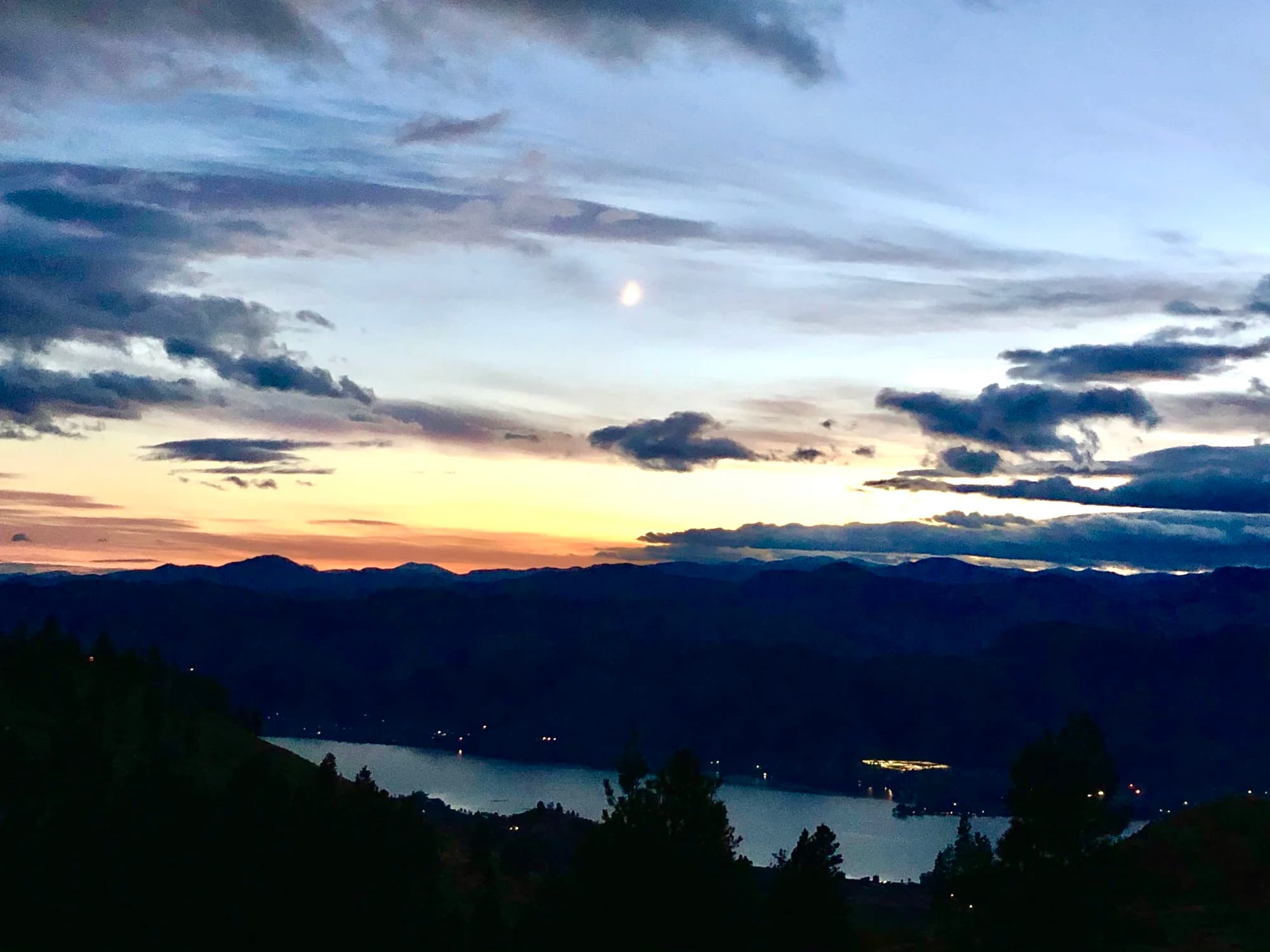 Osoyoos Lake at dusk with town lights, dramatic clouds and mountain silhouettes