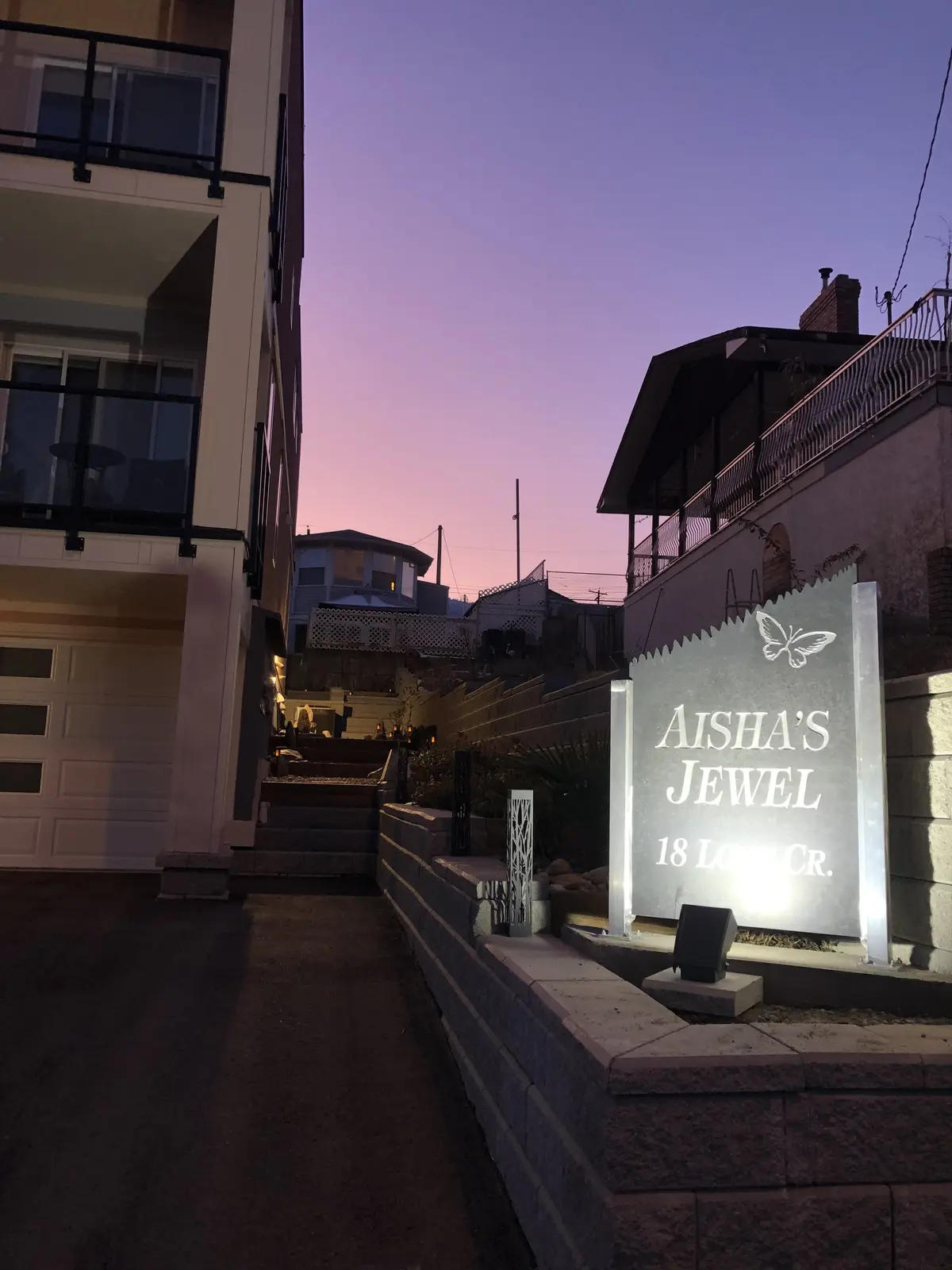 Aisha's Jewel property sign on deck against purple sunset sky in downtown Osoyoos