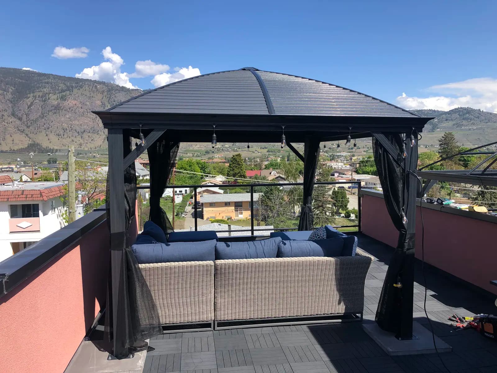 Aisha's Jewel private rooftop gazebo with blue outdoor sofa, curtains and panoramic mountain and town views