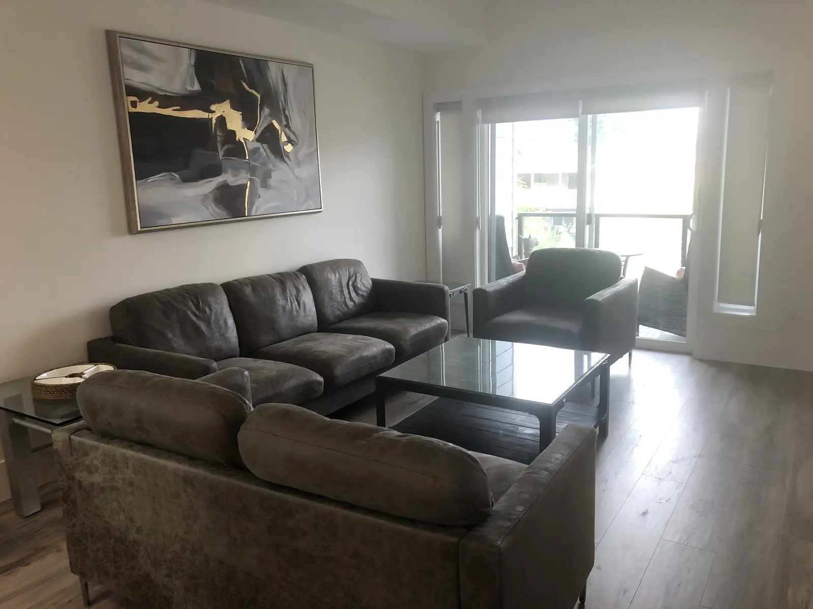 Aisha's Jewel family room with gray leather sofa, abstract art and balcony doors in natural light
