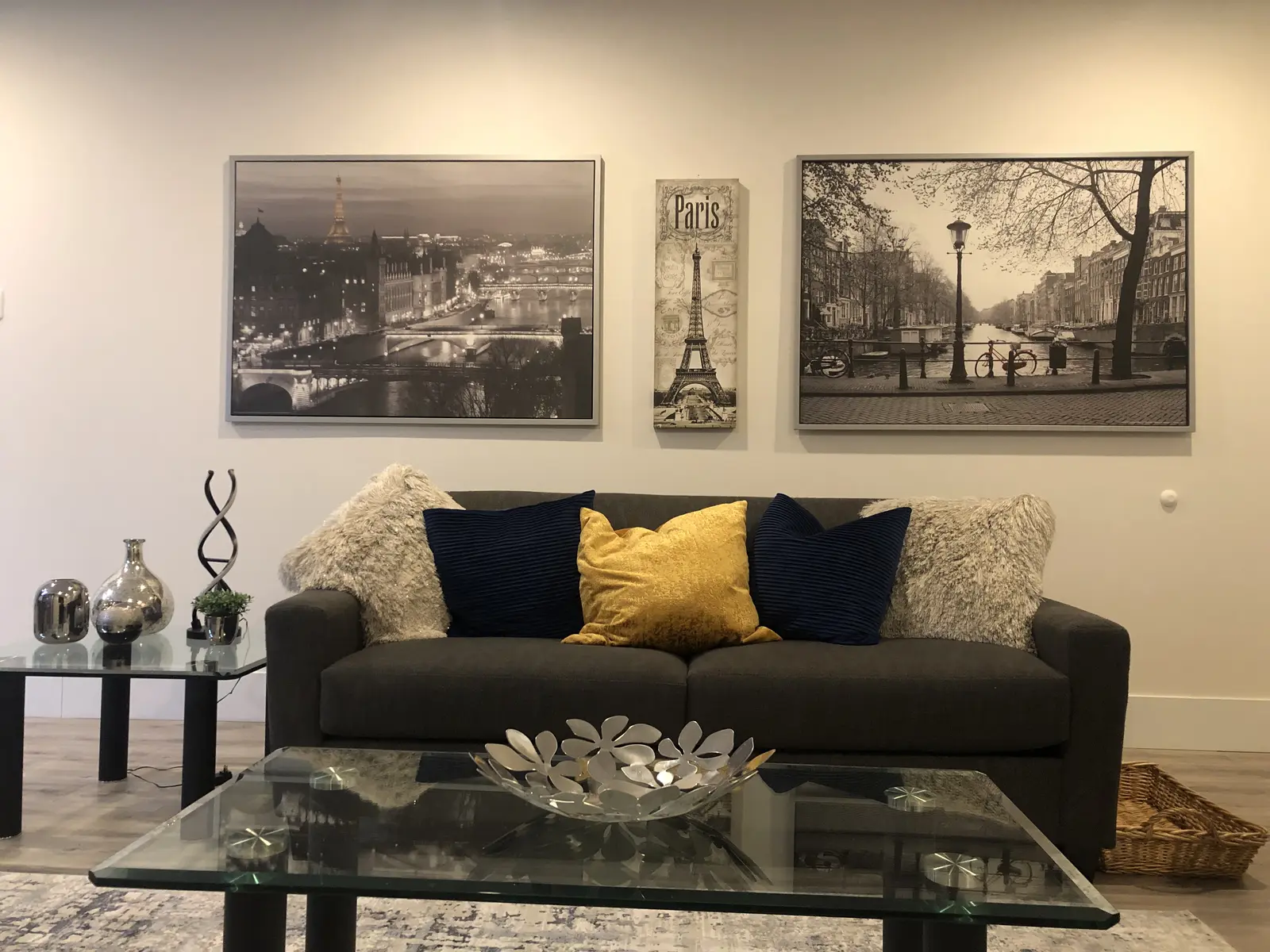 Aisha's Jewel living room with gray sofa, Paris and Amsterdam art prints and glass coffee table