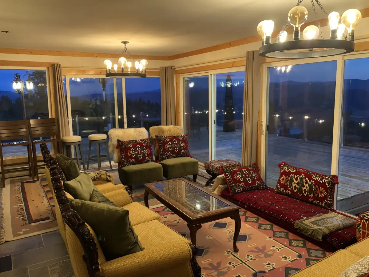 Vista Peak living room at evening with chandeliers, eclectic colorful furniture and Osoyoos Lake views through sliding doors